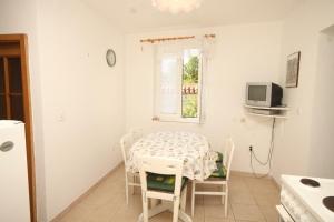 ein weißes Esszimmer mit einem Tisch und einem TV in der Unterkunft Holiday apartments Osor, Losinj - 8004 in Nerezine
