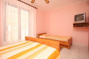 a bedroom with two beds and a tv on the wall at Apartment Susak 8047a in Susak