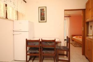 een keuken met een tafel en een witte koelkast bij Apartment Susak 8047a in Susak