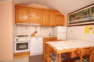 a kitchen with wooden cabinets and a table and a refrigerator at Apartments with WiFi Susak, Losinj - 8047 in Susak