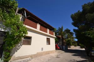 a building on a street with a palm tree at Apartments by the sea Mali Losinj (Losinj) - 7996 in Mali Lošinj