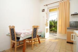 a dining room with a table and a television at Apartment Mali Losinj 7991b in Mali Lošinj