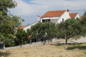a white house on a hill with trees at Apartments with a parking space Mali Losinj (Losinj) - 7969 in Mali Lošinj