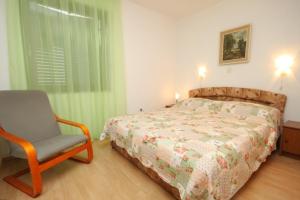 a bedroom with a bed and a chair and a window at Apartments with a parking space Mali Losinj (Losinj) - 7969 in Mali Lošinj