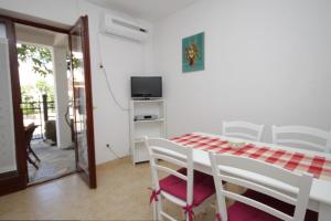 a white dining room with a table and chairs at Apartments with a parking space Mali Losinj (Losinj) - 7969 in Mali Lošinj