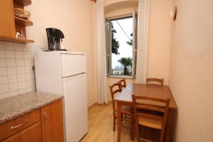 Apartments by the sea Opatija - 7830 في أوباتيا: مطبخ وغرفة طعام مع طاولة وثلاجة