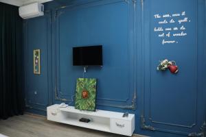 a room with a blue wall with a tv on it at NovART SeaVilla&Gallery Hotel in Sumqayıt