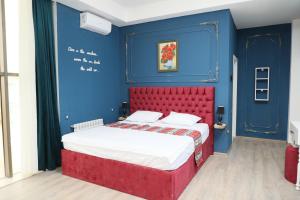 Habitación azul con cama con cabecero rojo en NovART SeaVilla&Gallery Hotel, en Sumqayit