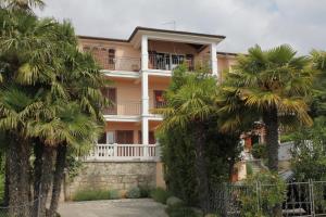 a building with palm trees in front of it at Apartments with a parking space Icici, Opatija - 7988 in Ičići