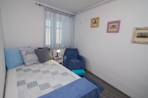 a bedroom with a bed and a blue chair at Apartments by the sea Veli Losinj, Losinj - 7959 in Veli Lošinj