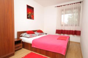 a bedroom with a pink bed and a window at Apartments with a parking space Mali Losinj (Losinj) - 7998 in Mali Lošinj