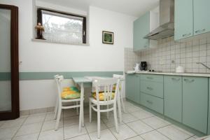 a kitchen with blue cabinets and a table and chairs at Apartments with a parking space Mali Losinj (Losinj) - 7998 in Mali Lošinj