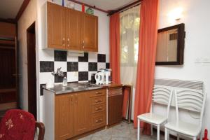 uma cozinha com um lavatório e um balcão com cadeiras em Apartments by the sea Mali Losinj (Losinj) - 8002 em Mali Lošinj