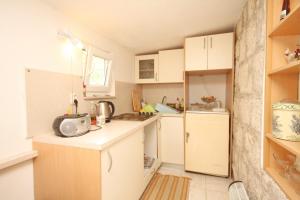 a small kitchen with white cabinets and a refrigerator at Holiday apartments Lastovo - 7790 in Lastovo