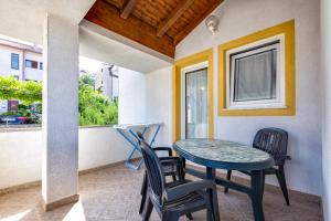 a porch with a table and chairs and a window at Apartments with a parking space Mali Losinj (Losinj) - 8026 in Mali Lošinj