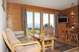 een woonkamer met een tafel, stoelen en een televisie bij Favorite Parterre in Riederalp