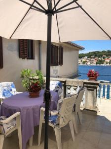 einen Tisch mit einem lila Tischtuch und einem Regenschirm in der Unterkunft Apartments by the sea Mali Losinj (Losinj) - 8006 in Mali Lošinj