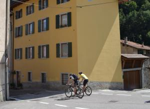 duas pessoas a andar de bicicleta em frente a um edifício amarelo em Casa Ledro em Ledro