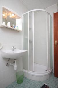 uma casa de banho branca com um chuveiro e um lavatório. em Rooms with a parking space Veli Brgud, Opatija - 7840 em Jurdani