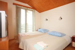 um quarto com uma cama com almofadas azuis e uma televisão em Rooms with a parking space Veli Brgud, Opatija - 7840 em Jurdani