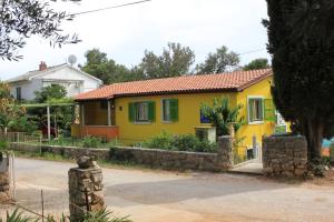a yellow house with green shutters on a street at Apartments with a parking space Artatore, Losinj - 7938 in Čunski