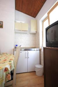 a small kitchen with a table and a television at Apartments with a parking space Artatore, Losinj - 7938 in Čunski