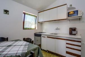 una cucina con armadi bianchi, lavandino e tavolo di Apartments by the sea Artatore, Losinj - 7934 a Čunski