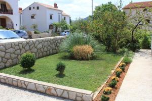 a garden with plants and a stone retaining wall at Apartments with a parking space Cres - 7983 in Cres +11 photos
