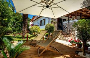 a pair of chairs and an umbrella on a deck at Apartments by the sea Artatore, Losinj - 8020 in Čunski