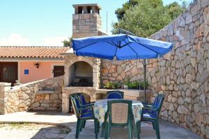 une table avec un parasol bleu et des chaises ainsi qu'un mur en pierre dans l'établissement Apartments with a parking space Veli Losinj, Losinj - 8029, à Veli Lošinj