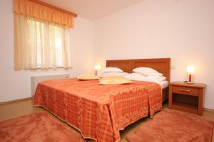 een slaapkamer met een groot bed en een oranje deken bij Apartments with a parking space Cres - 7985 in Cres