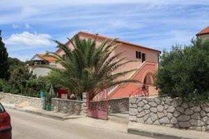 a house with a palm tree in front of a street at Apartments by the sea Mali Losinj (Losinj) - 8027 in Mali Lošinj