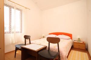 a bedroom with a bed with two chairs and a table at Apartments by the sea Mali Losinj (Losinj) - 8027 in Mali Lošinj