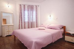 1 dormitorio con 1 cama con sábanas rosas y espejo en Seaside holiday house Mavarstica, Ciovo - 9206 en Trogir