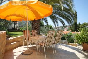 una mesa y sillas bajo una sombrilla en un patio en Seaside holiday house Mavarstica, Ciovo - 9206 en Trogir