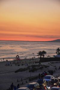 a sunset at the beach with cars parked on the beach at Rock’s Beach Spot Suit in Costa da Caparica