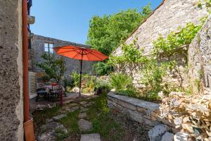 een patio met een oranje paraplu in een tuin bij Apartments with parking space Zrnovo, Korcula - 9239 in Korčula