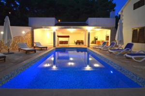 una piscina con acqua blu in un cortile posteriore di notte di Seaside family friendly house with a swimming pool Brna - Vinacac, Korcula - 9266 a Prižba