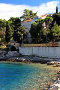a body of water with a white fence and a building at Apartments by the sea Medvinjak, Korcula - 9268 in Korčula