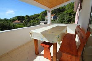 a table and a chair on a balcony with a view at Family friendly apartments with a swimming pool Smokvica, Korcula - 9161 in Smokvica