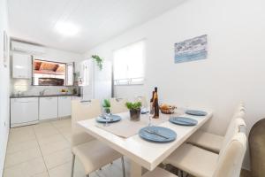 a white kitchen and dining room with a white table and chairs at Seaside house for families with children Cove Stratincica, Korcula - 9265 in Vela Luka