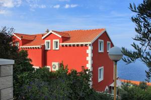 ein rotes Haus mit dem Ozean im Hintergrund in der Unterkunft Seaside apartments with a swimming pool Prigradica, Korcula - 9290 in Prigradica