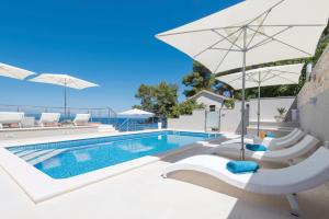 a pool with chairs and an umbrella next to a swimming pool at Seaside apartments with a swimming pool Prigradica, Korcula - 9290 in Prigradica