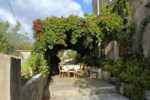 a table and chairs under an arch with roses at Holiday house with a parking space Zrnovo, Korcula - 9213 in Korčula +13 photos