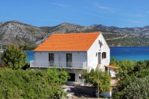 a white house with an orange roof and the water at Apartments by the sea Kneza, Korcula - 9185 in Račišće