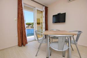 a dining room with a table and chairs and a balcony at Seaside apartments with a swimming pool Lumbarda, Korcula - 9303 in Lumbarda