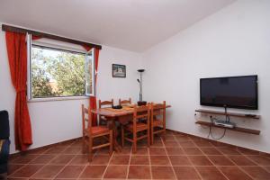 a dining room with a table and a flat screen tv at Apartments by the sea Brna, Korcula - 9231 in Smokvica
