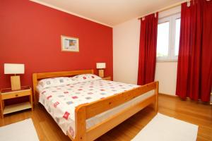 um quarto com uma cama de madeira e paredes vermelhas em Apartments by the sea Lumbarda, Korcula - 9260 em Lumbarda