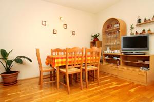 uma sala de jantar com uma mesa e cadeiras e uma televisão em Apartments by the sea Lumbarda, Korcula - 9260 em Lumbarda