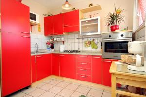 Apartments by the sea Lumbarda, Korcula - 9260 في لومباردا: مطبخ احمر مع اجهزه بيضاء ودواليب حمراء